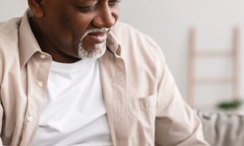 A man sitting down looking at his stomach.