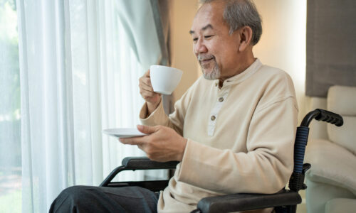 A man in a wheelchair holding a cup of coffee.